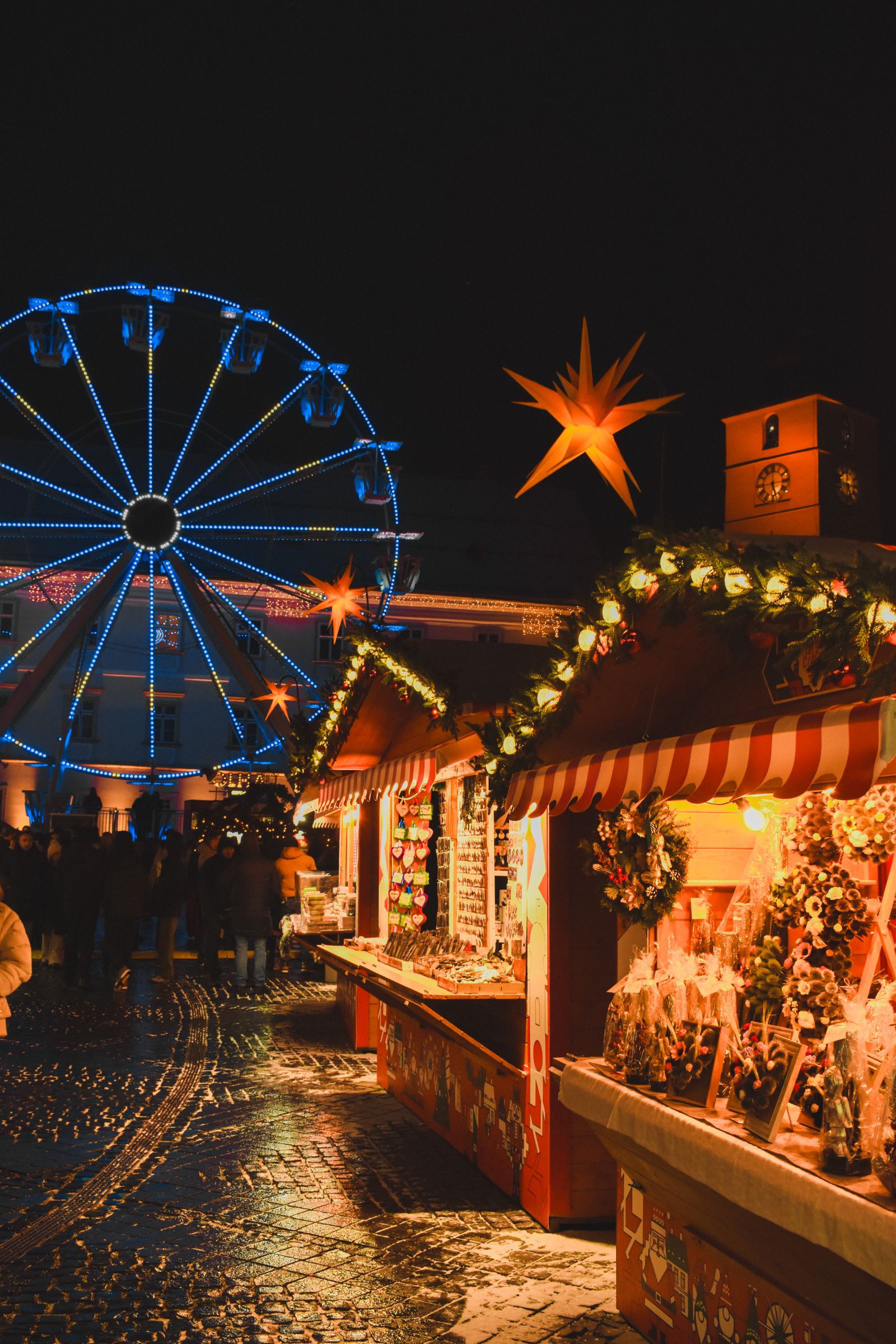 Marché de Noël illuminé en soirée avec une grande roue et des chalets